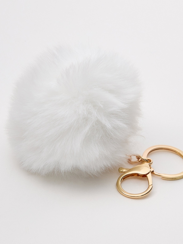 White pompom keychain foreground with a model